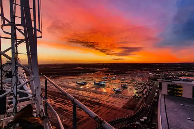 Dit is een sfeerfoto vanuit een kraan tijdens golden hour met zonsondergang en vliegtuigen op de luchthaven.