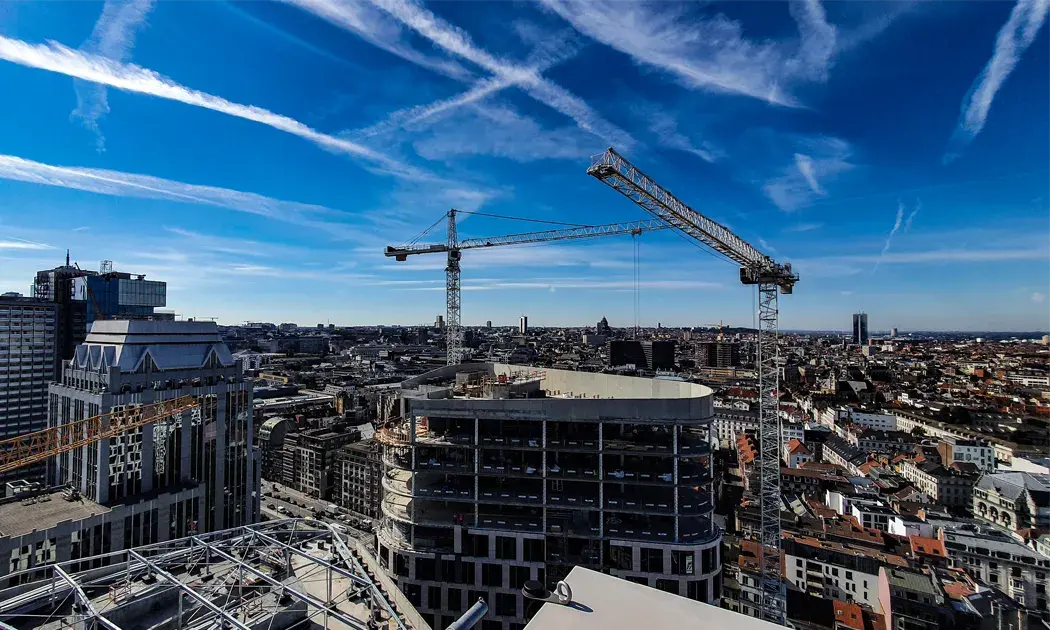 Dit zijn 2 torenkranen vanuit kikkerperspectief met blauwe lucht en wolken op de achtergrond