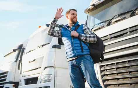 This is a pedestrian in front of a few trucks as an example of the dangers of not being seen by truck drivers